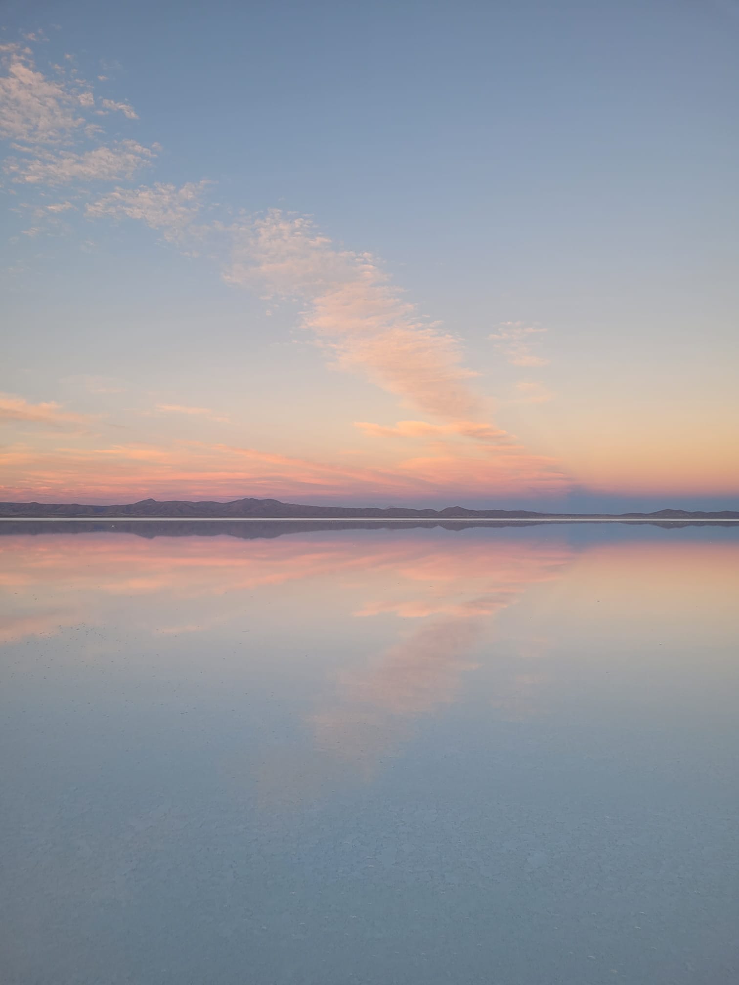 Coucher de soleil rose et orange reflété dans la zone humide du salar d'Uyuni