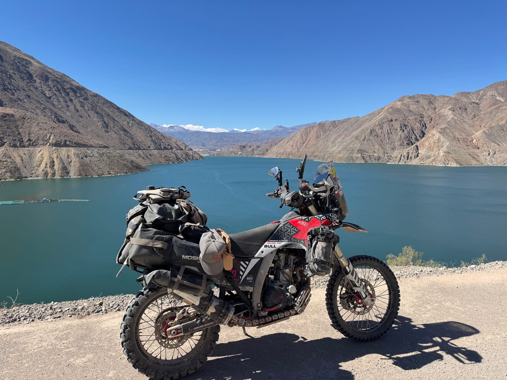 Moto chargée garée au bord d'un lac turquoise sur la route vers Ilo