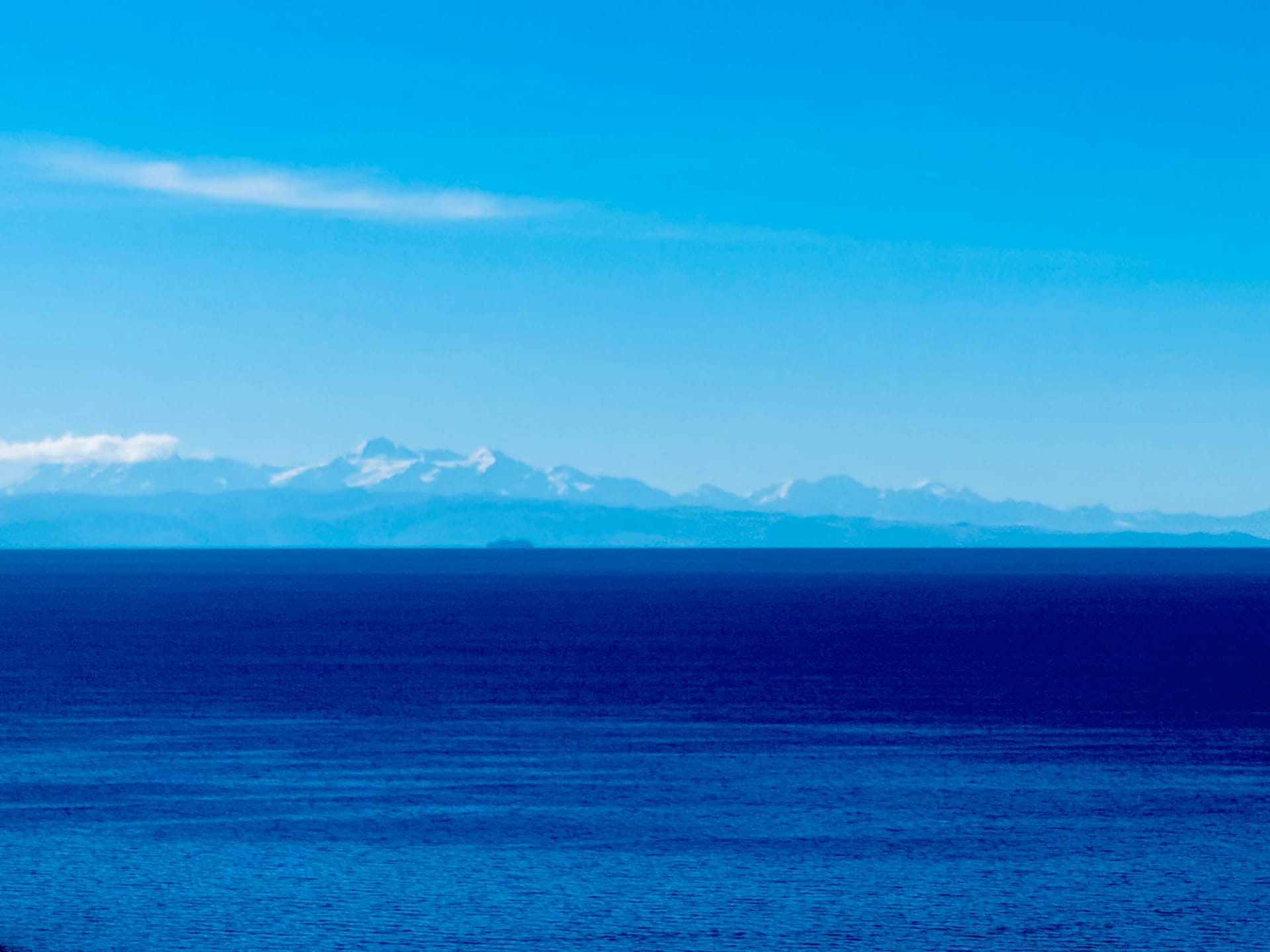 Lac Titicaca bleu profond et Cordillère Royale enneigée à l'horizon depuis l'île Amantani