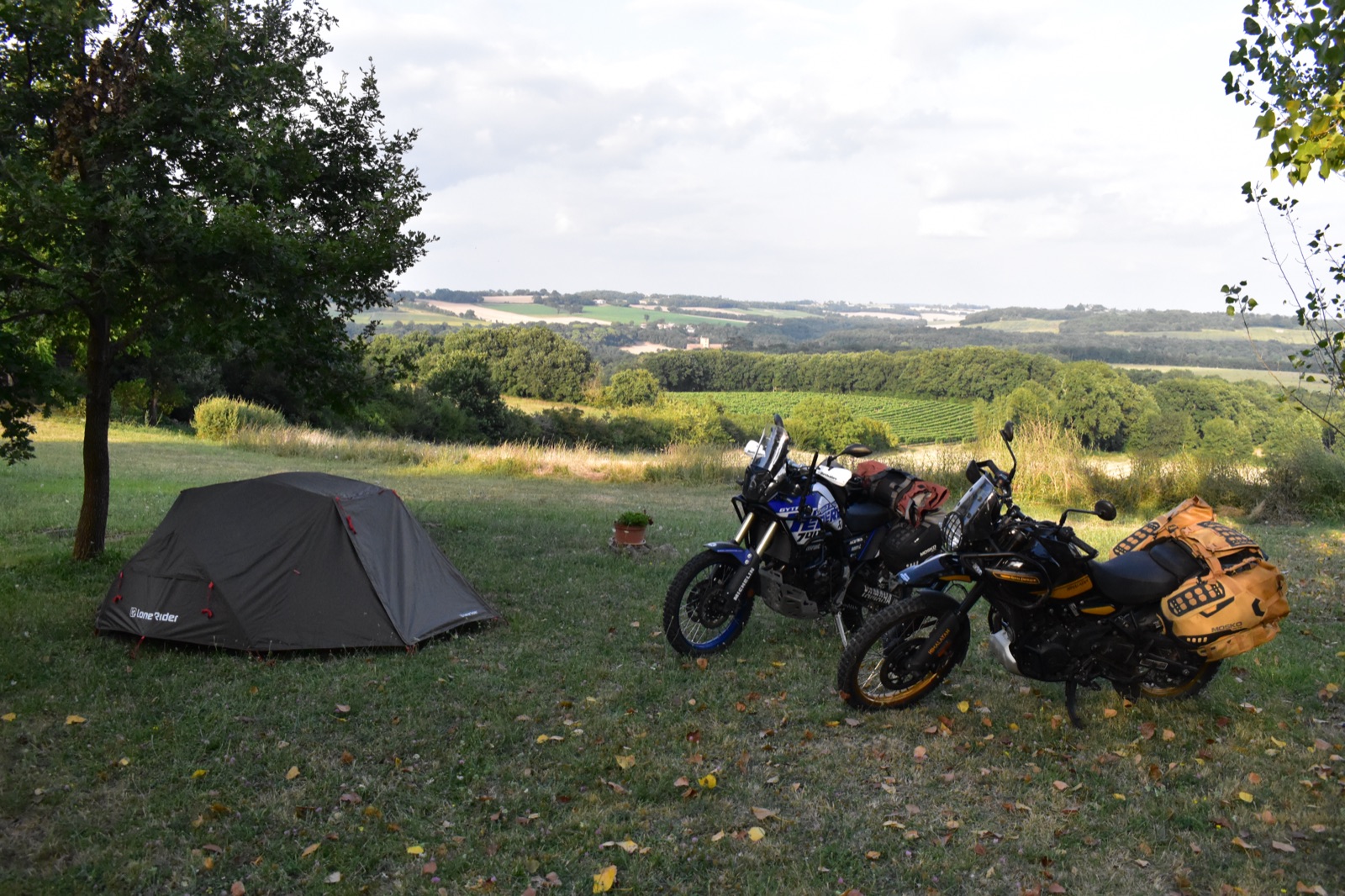 La tente Lone Rider ADV Tent kaki montée dans un pré, à côté de nos deux motos
